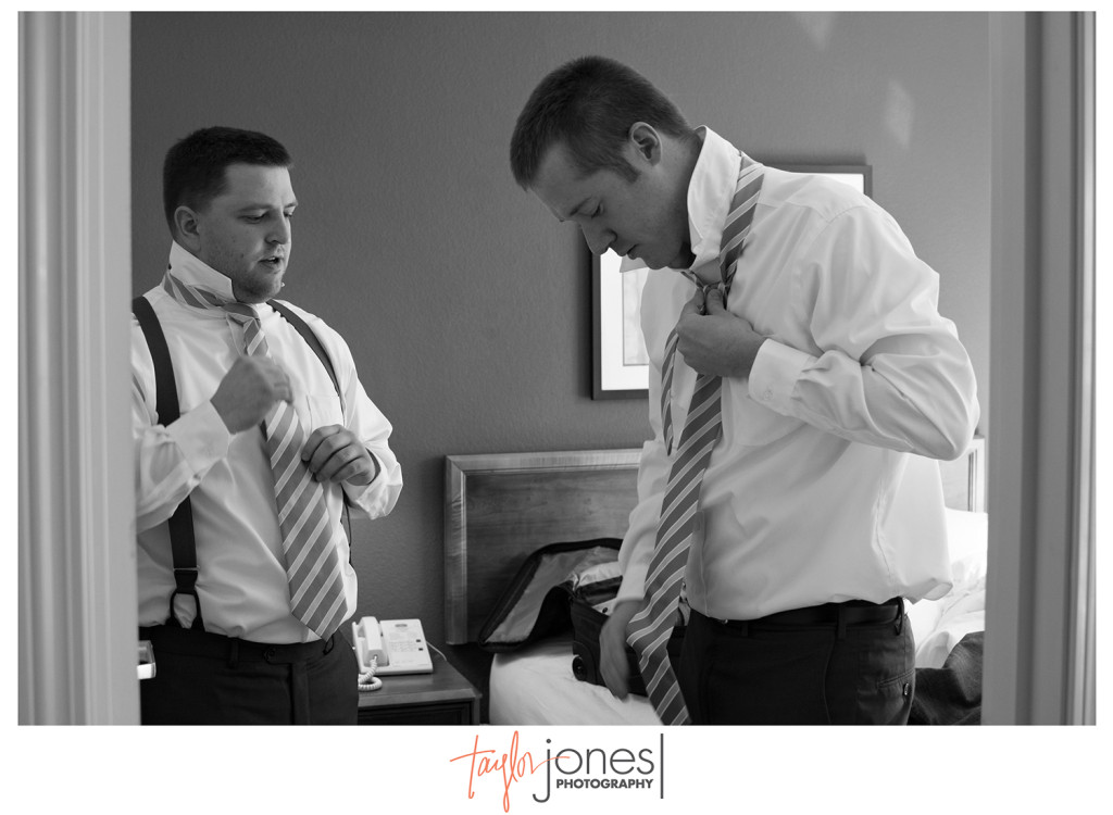 Groom and groomsman tying tie