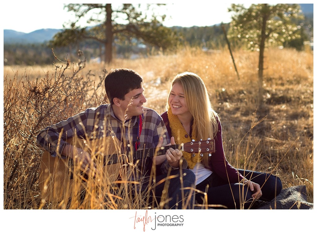 Couple sitting in a field playing guitar