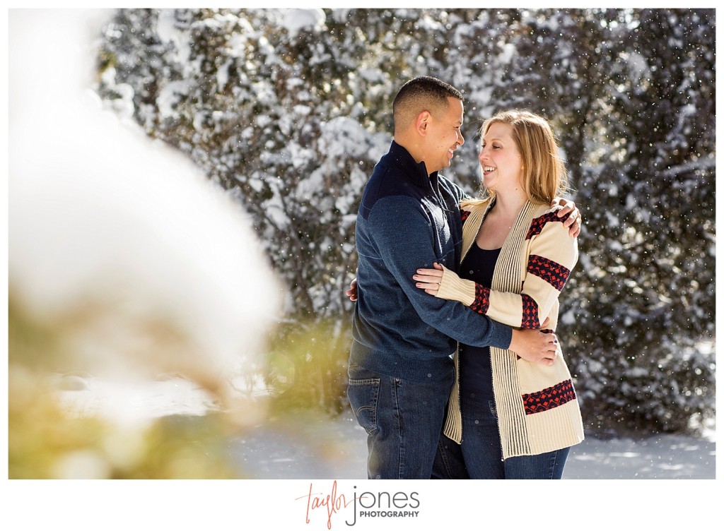 Couple with snow falling around them at Mt. Falcon winter engagement shoot