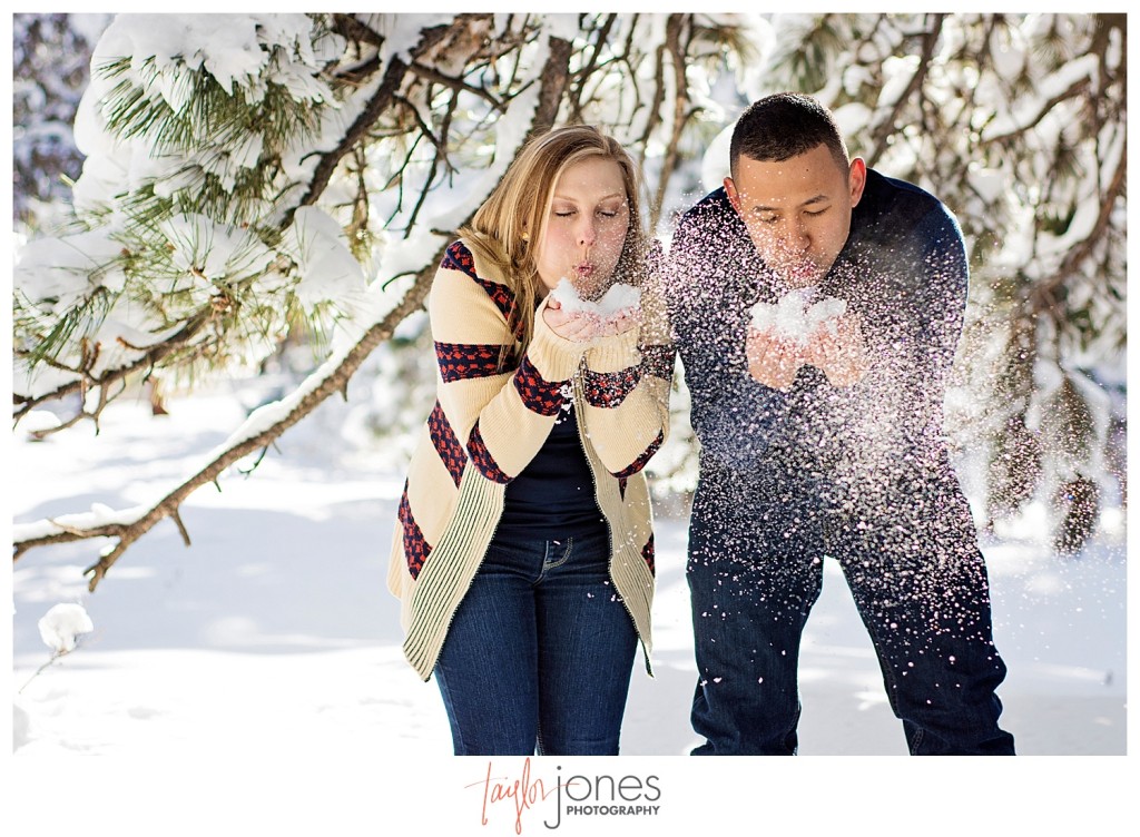 Couple blowing snow at winter engagement shoot at Mount Falcon Morrison Colorado
