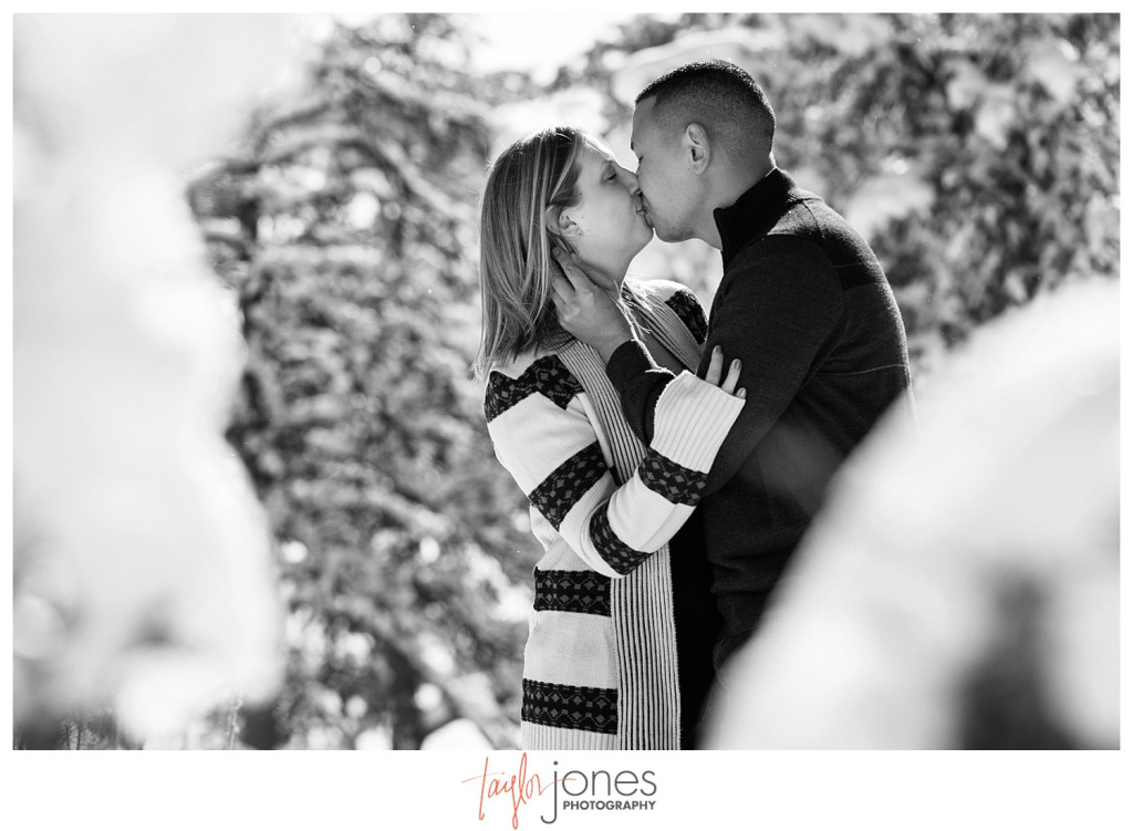 Black and white image of couple kissing in the trees at Mt. Falcon engagement shoot, winter